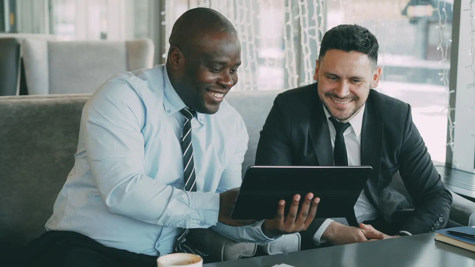 Zwei Geschäftspartner besprechen nach der Messe die nächsten Schritte am Tablet